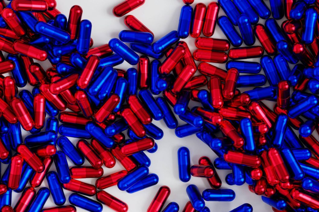 Blue and red capsule pills on white background, healthcare medical concept, antibiotics and cure